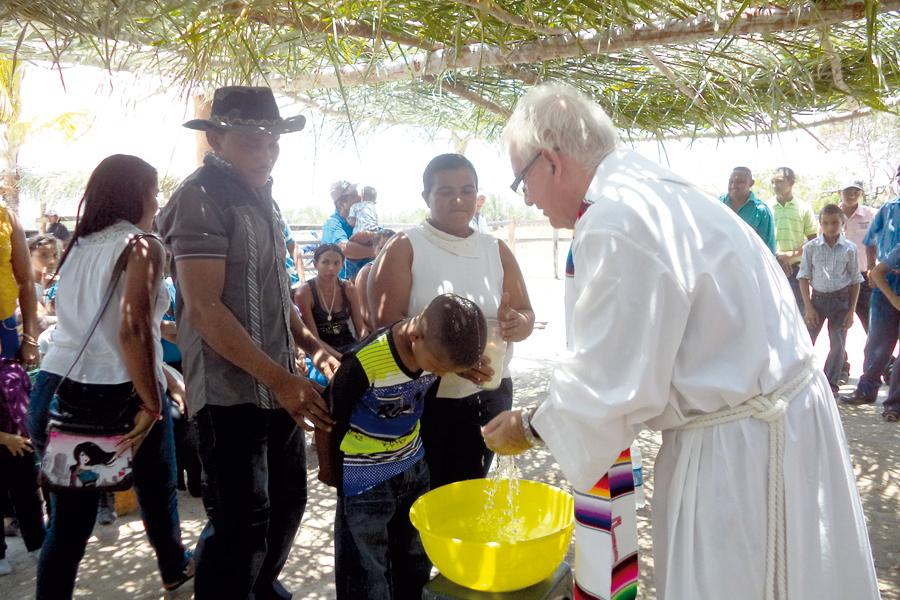 El sacerdote malagueño Manuel Lozano bautiza a un niño en el Caserío de Los Asientos en Caicara del Orinoco